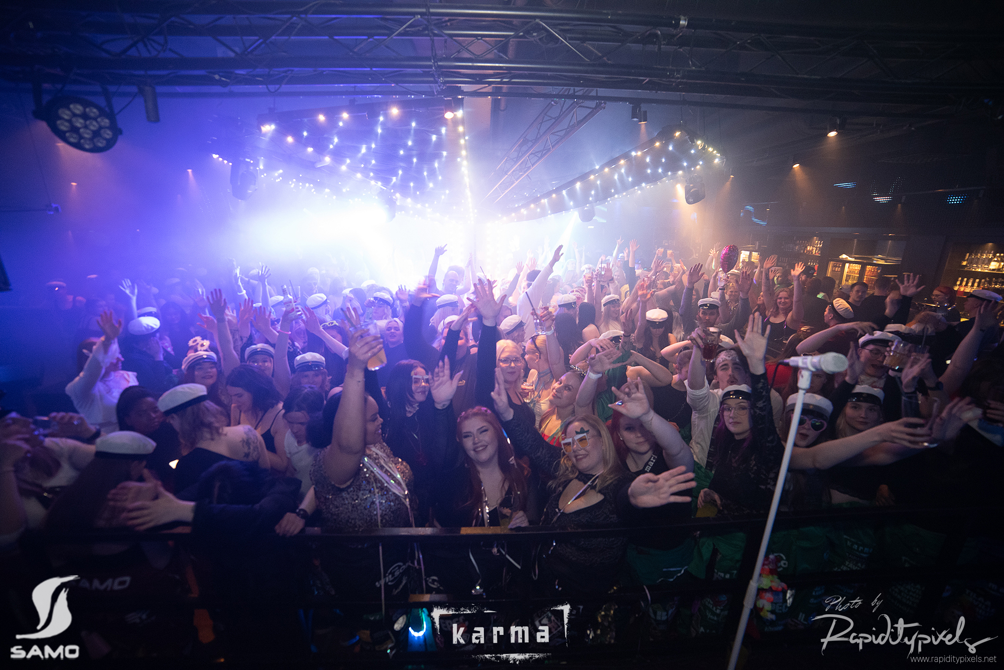 SAMOn Wapu 2023. Esiintyjän näkökulmasta katsottuna juhliva yleisö heiluttaa käsiään ilmassa, valojen heijastuessa tanssivan väkijoukon päälle.